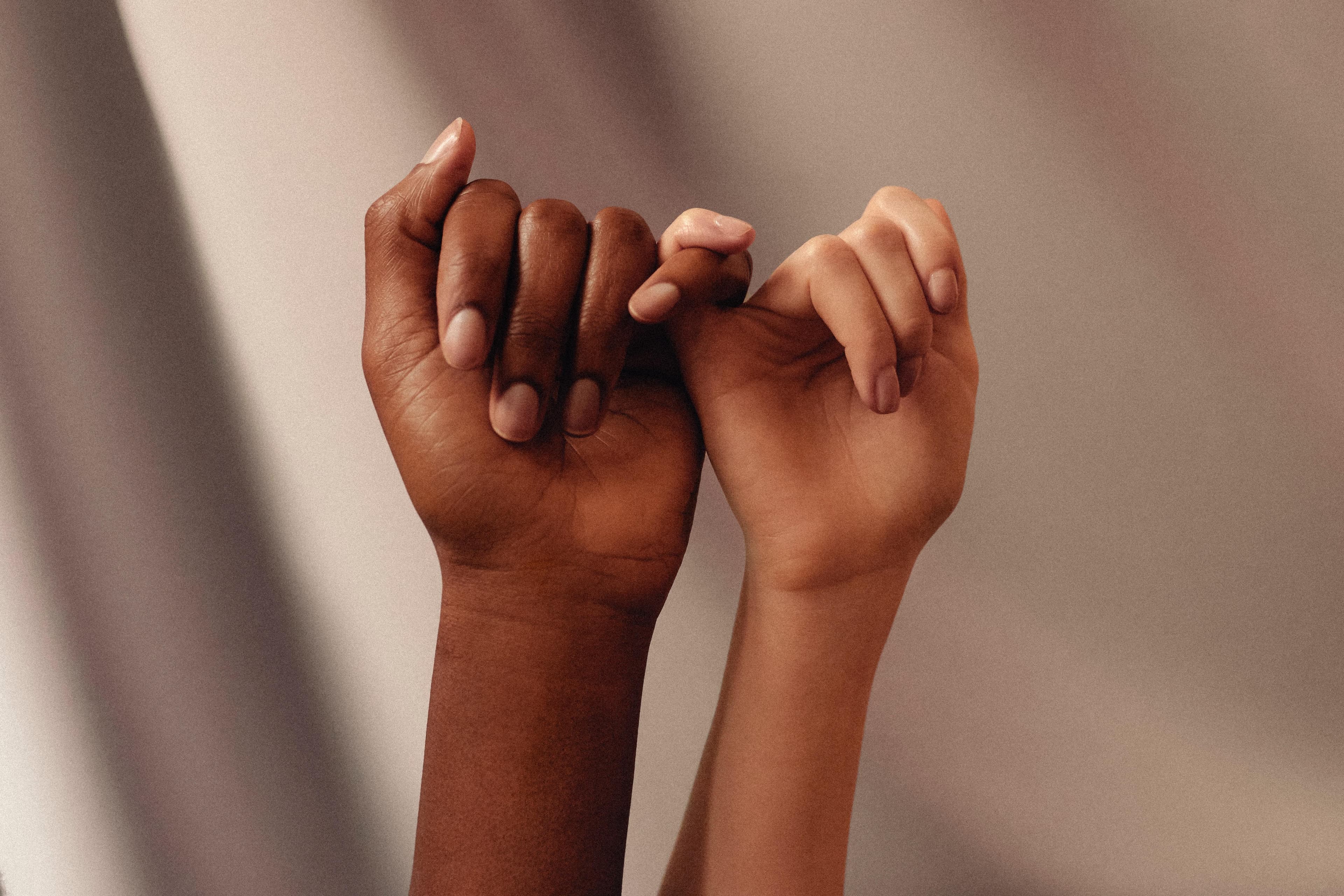 Two hands pinky-promising, representing inclusive connection
